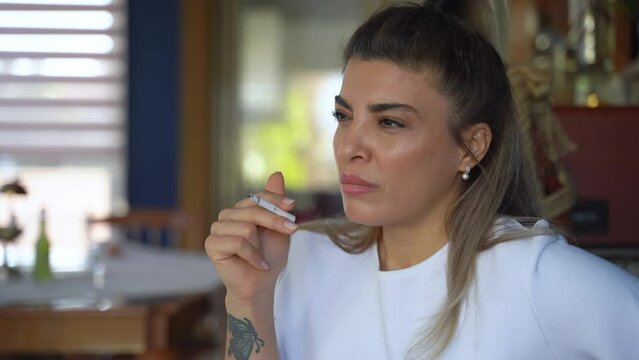 Middle-eastern woman smoke cigarette with lighter tobacco at home, unhealthy lifestyle concept.