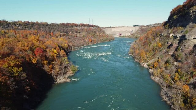 A wild river flowing through a canyon in Niagara Glen with a view of the dam. Sunny autumn day as seen from a drone, Canada