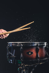 A man plays the snare drum against a dark background.