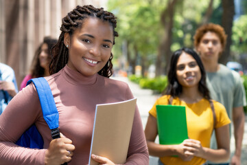 Laughing black female student with dreadlocks and group of latin american and caucasian young adults