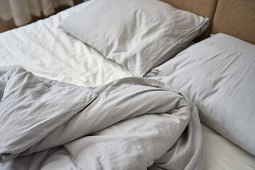 Unmade bed after sleeping. Crumpled bed with pillows, blanket and crumpled sheets in bedroom. Morning housekeeping