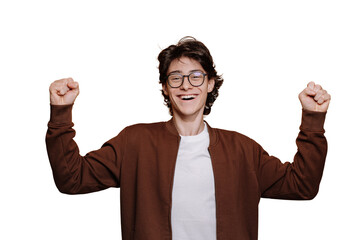 Amazed German teenager in glasses, brown jacket and white t-shirt rises clenched fists in winner...
