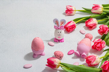 Pink tulips with Easter eggs on light stone concrete background. Festive concept, greeting card