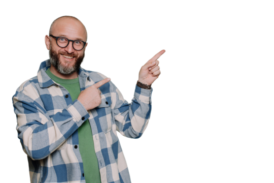 Positive Caucasian bald beardy man in plaid shirt pointing any index finger at empty space looks at camera against transparent background. Excited Italian male in glasses, teacher. Mockup, promo. - Powered by Adobe