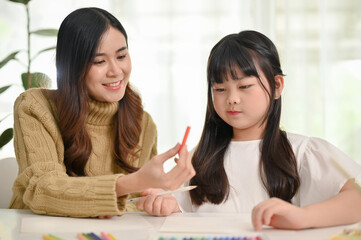 Happy Asian mom enjoys spending creativity time with her little daughter at home