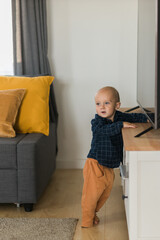 Caucasian baby newborn infant making first steps. Cute toddler kid child son boy learning walking creeping on living room. Childcare and childhood concept