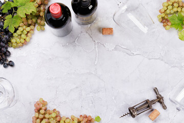 Wine glasses, bottles and grapes on marble table