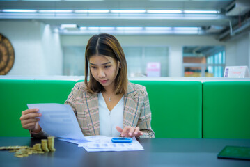 Young beautiful asian business woman sitting and looking at company financial documents, Digital marketing.