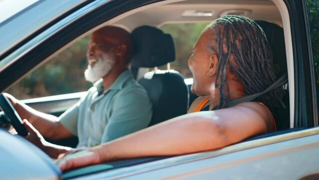 View through passenger window as senior couple go on journey sightseeing in car together - shot in slow motion
