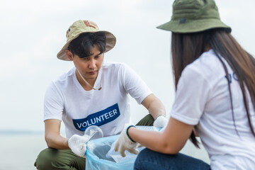 Fototapeta premium Male and female volunteers collecting garbage, conducting environmental cooperation, saving world reducing global warming, Volunteers clean plastic bag waste in natural attractions.