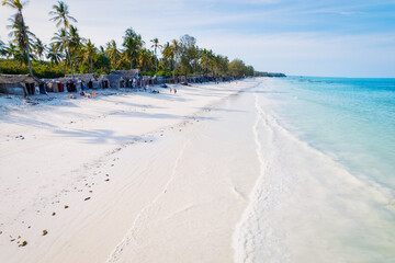An aerial view of Zanzibar's sandy beaches captures the essence of a tropical paradise with palm trees, umbrellas, white sand, and the serene blue waters of the Indian Ocean.