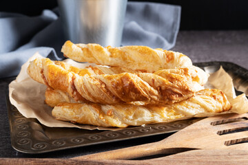 Puff pastry cheese sticks on a silver tray close-up.