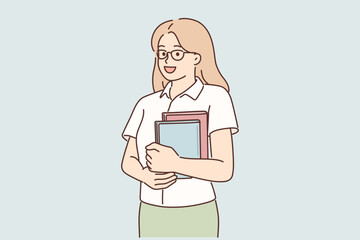 Young girl student stands with books in hands posing with glasses and looking at screen © Valery