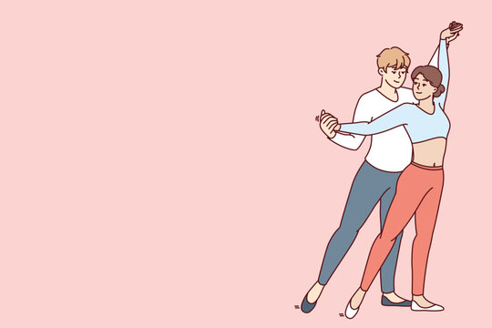 Young couple performs passionate dance semba salsa or kizomba bachata wishing to become professional dancers and perform in front of audience. Man hugging woman from behind performing salsa dance 
