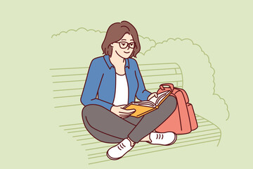 Teenage girl is reading book sitting on park bench enjoying good summer weather and intriguing plot of novel or fiction. Young woman spends leisure time outdoors doing self-education