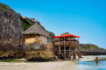 Zanzibar's beaches offer a picture-perfect setting for a summer vacation, as seen from an aerial view, with palm trees, umbrellas, white sand, and the crystal-clear waters of the Indian Ocean.