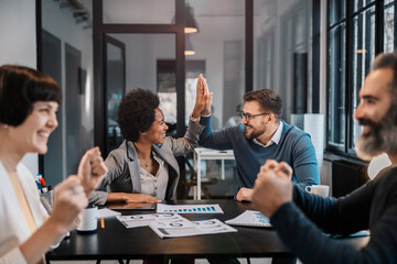 A multiracial businesspeople is celebrating success on project. Both of them is giving high five.