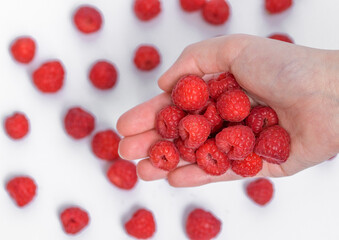 Obraz premium Maliny trzymane w dłoniach na tle rozmytych owoców 