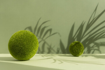 Minimal abstract scene with grass balls and the shadow of palm leaves on a green background. Premium empty podium for product promotion, beauty, natural eco cosmetic. Showcase, display case.