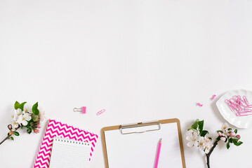 Stylish flat lay women's workplace with notebooks, tablet, pen and spring apple blossoms on a white background with copy space