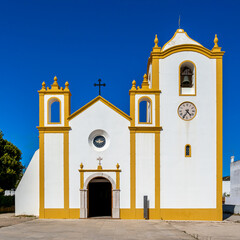 The yellow framed white front facade of church Nossa Senhora da Luz de Lagos shines in the sun in...