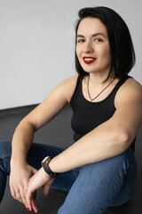 Brutal girl with black hair and red lipstick on her lips wearing jeans and boots