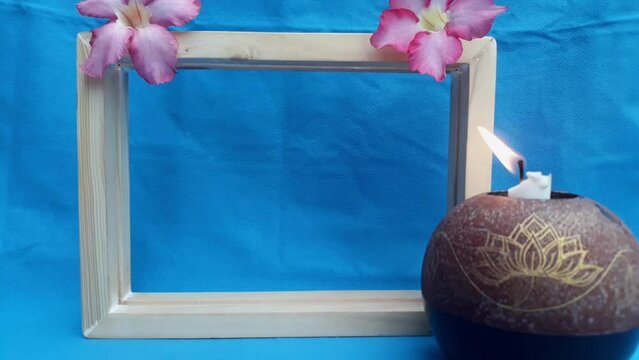 wooden picture frame square box in gradient blue background with flower head Adenium beautiful red pink tropical flower called desert rose and candle holder still life concept
