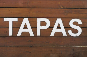 Tapas, an Appetizer or Snack in Spanish Cuisine, White Text on Wooden Background