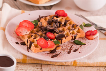 Waffles with strawberries and chocolate cream.