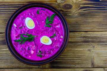 Plate with beet soup on a wooden table. Top view