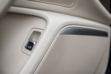Trunk opening button in a beige leather interior of a modern car. Trunk button. Car speaker...
