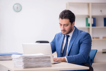 Naklejka premium Young male employee and too much work in the office
