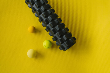 Equipment for MFR. Balls and roll on a yellow mat for yoga or fitness. Self-massage tools