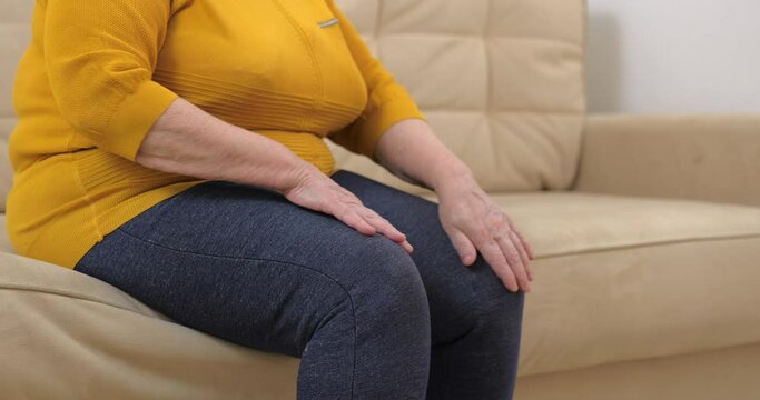Senior fat woman with serious legs and knee pain massaging knee