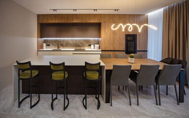 Beautiful modern kitchen in a luxury apartment with island table and chairs. Modern interior of kitchen in private house with panoramic windows and marble floor.