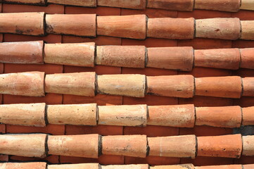 Red and orange roof tiles texture pattern on roof of an old historical building