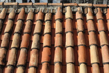 Red and orange roof tiles texture pattern on roof of an old historical building