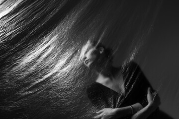 Thoughtful young brunette standing behind film curtain