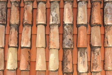 Red and orange roof tiles texture pattern on roof of an old historical building