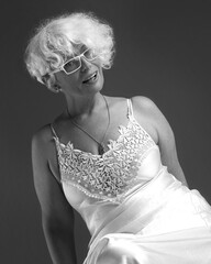 Black and white portrait of smiling mature woman in lace negligee and glasses - obrazy, fototapety, plakaty