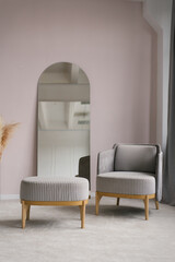 Classic modern grey armchairs, an ottoman in the living room interior and a mirror