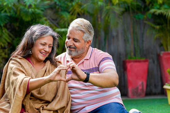 Indian Senior Couple Smiling And Making Heart Shape With Hand.