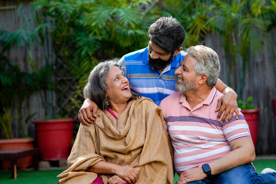 Indian senior couple sitting at outdoor with young man