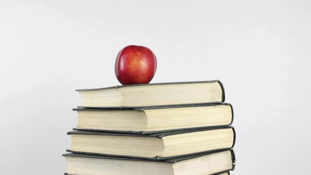 A stack of books and a red apple rotating