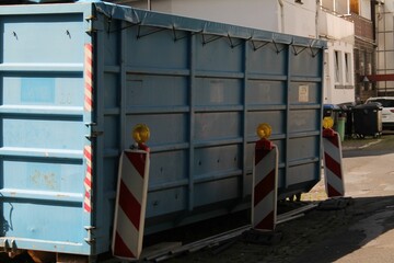 Metal trash container in the middle of a city on a sunny day