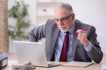 Old male employee working in the office