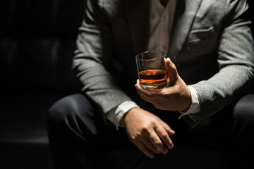 Businessman sitting and holding glass of whiskey