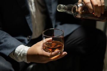 Businessman sitting and holding glass of whiskey