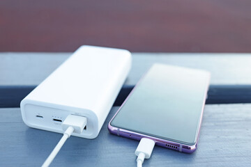 phone is charged from the power bank, portable charger on the bench