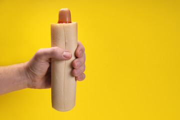 french hot dog with ketchup sauce in hand on yellow background